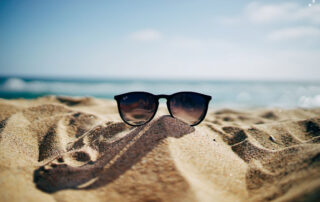 Sonnenbrille am Strand vor blauem Himmel